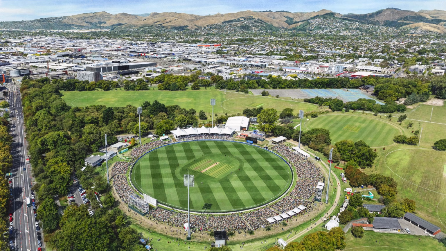 Wide landscape illustration of Hagley Oval cricket ground with a packed stand and green outfield under daylight