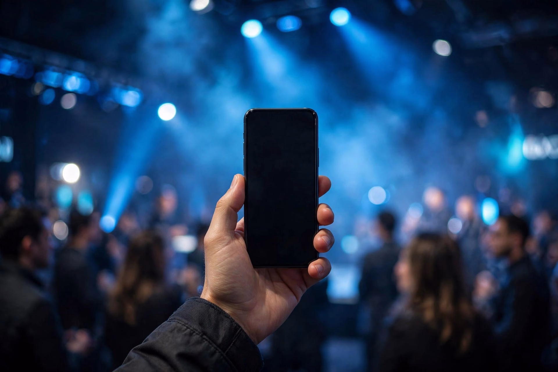 Person holding a smartphone under bright stage lights at a technology launch event