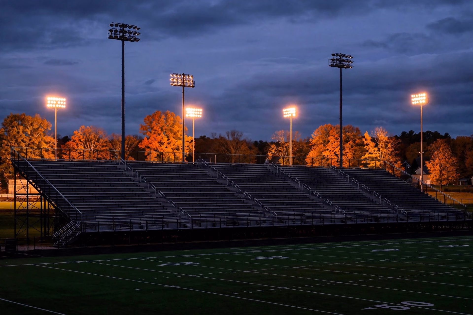 Empty stadium bleachers at dusk in a Connecticut high school football stadium.